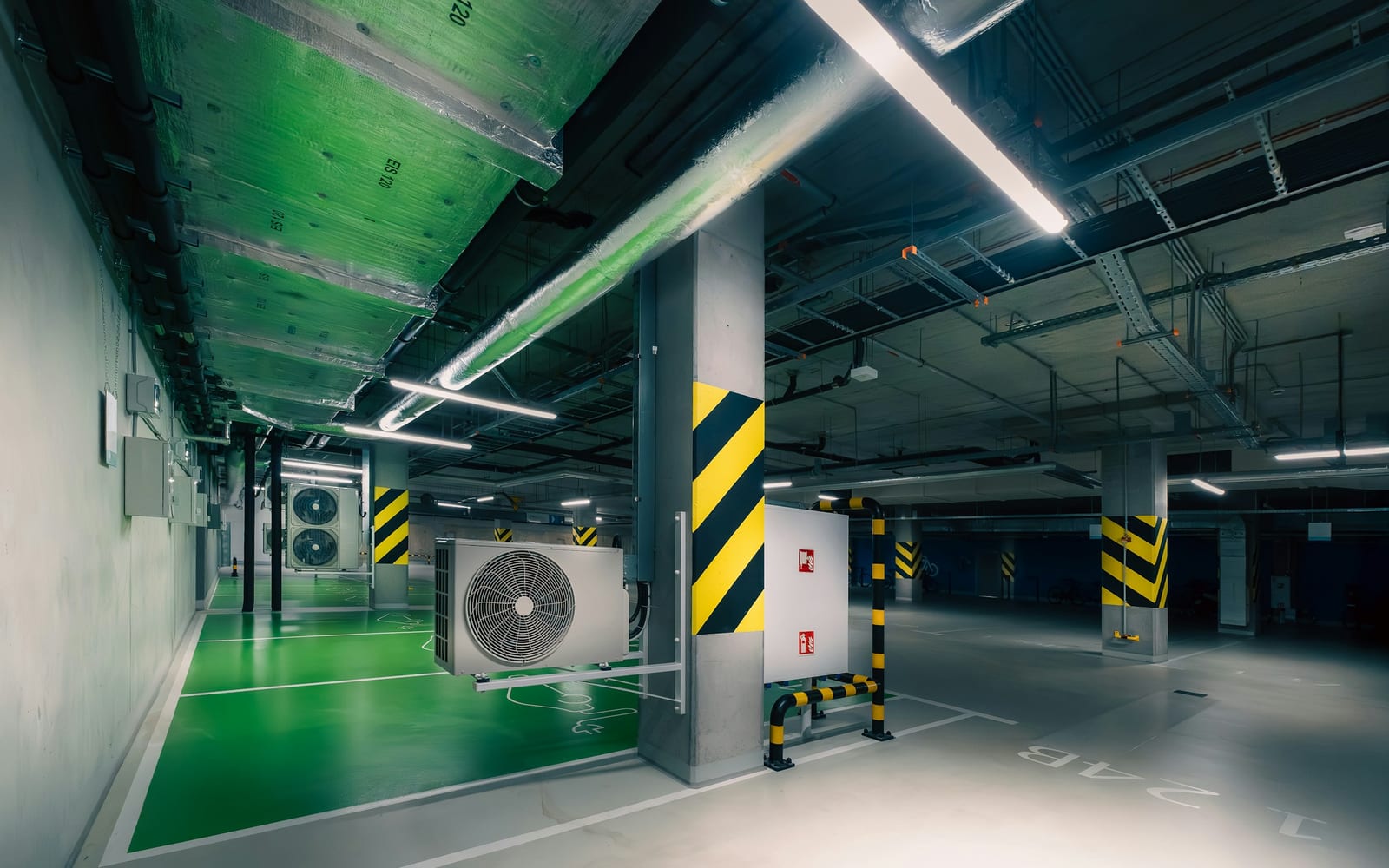 Modern parking garage interior with exposed concrete and ventilation systems.