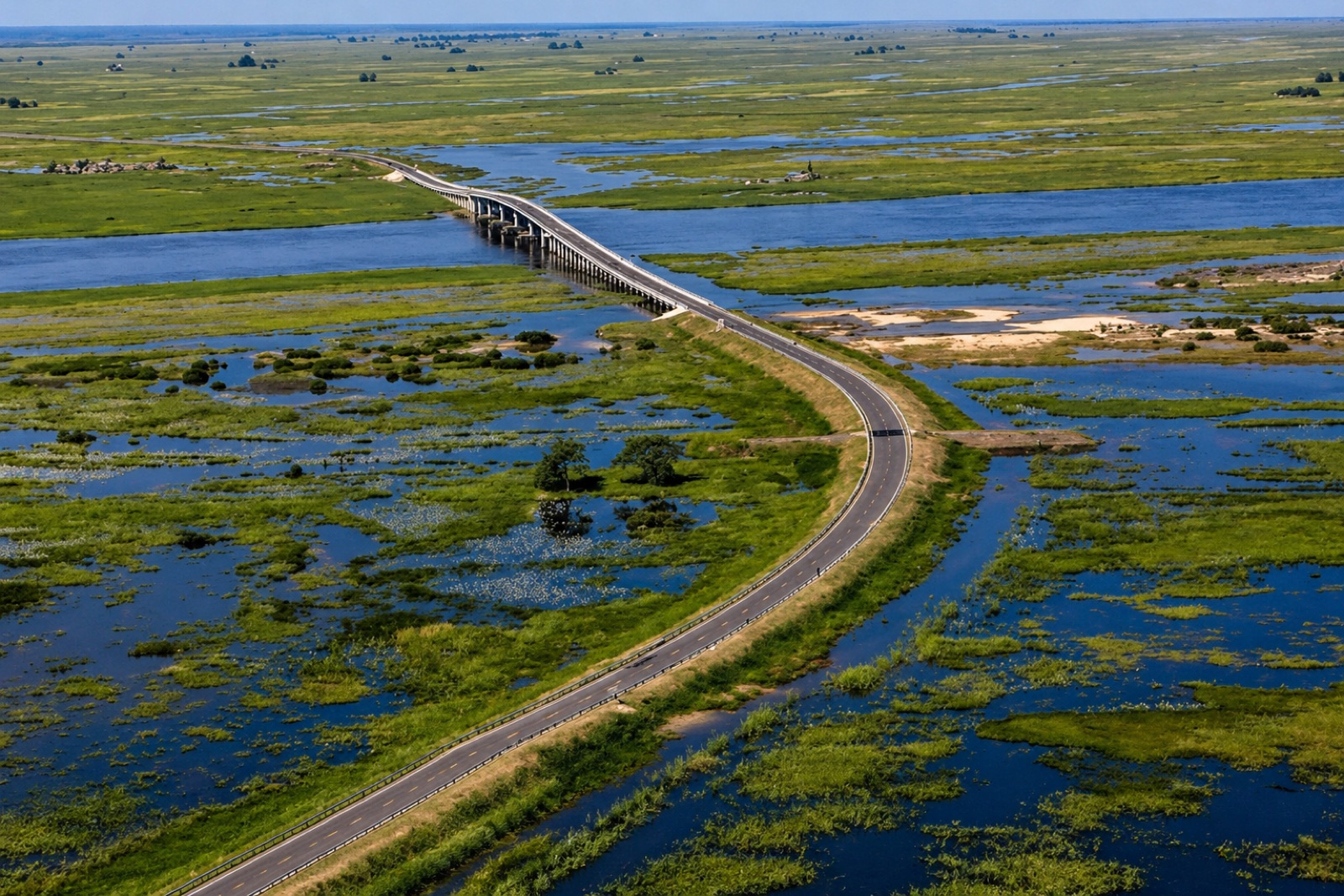 Aerial view of a Mongu–Kalabo Road bridge crossing a Zambezi tributary, with the Barotse Floodplain extending to the horizon.